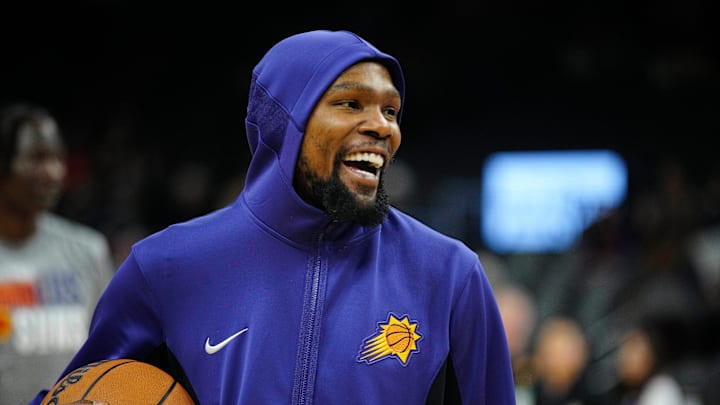 Suns forward Kevin Durant laughs as he takes the court to play the Raptors prior to a game at the Footprint Center.