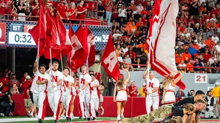 Sep 20, 2024; Lincoln, Nebraska, USA; Nebraska Cornhuskers cheerleaders carry flags across the field after a touchdown against the Illinois Fighting Illini during the first quarter at Memorial Stadium.