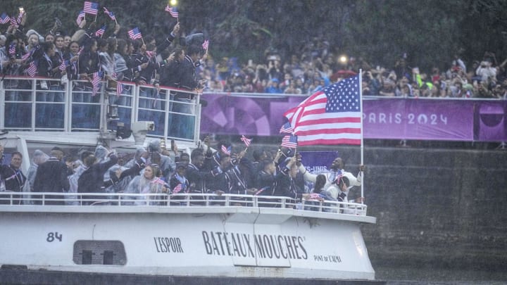 July 26, 2024; Paris, FRANCE; United States flag bearer LeBron James waves the flag of Greece on the team boat along the Seine River during the Opening Ceremony for the Paris 2024 Olympic Summer Games. Mandatory Credit: Kyle Terada-Imagn Images