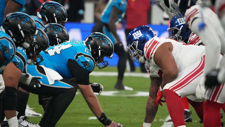 Nov 10, 2024; Munich, Germany; Helmets at the line of scrimmage as Carolina Panthers guard Cade Mays (64) snaps the ball against the New York Giants in the first half during the 2024 NFL Munich Game at Allianz Arena. Mandatory Credit: Kirby Lee-Imagn Images