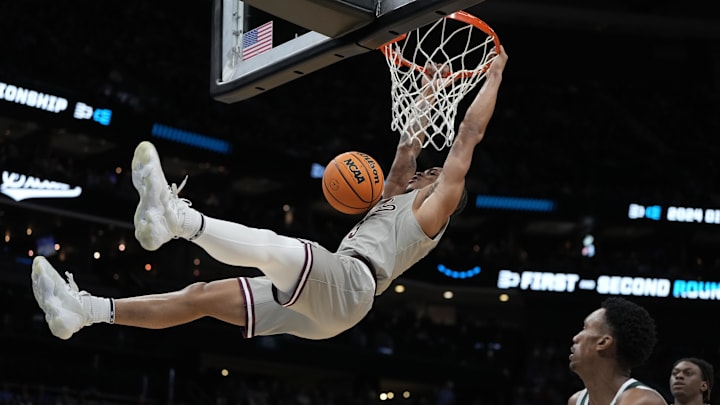 March 21, 2024, Charlotte, NC, USA; Mississippi State Bulldogs guard Shakeel Moore (3) hangs onto the rim after a dunk against the Michigan State Spartans in the first round of the 2024 NCAA Tournament at the Spectrum Center. Mandatory Credit: Bob Donnan-USA TODAY Sports
