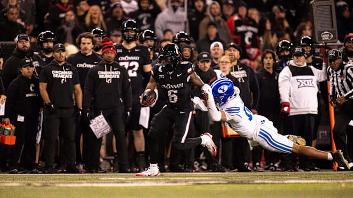 Cincinnati Bearcats running back Evan Pryor (6) brakes a tackle attempt by BYU Cougars linebacker Isaiah Glasker (16) in the fourth quarter of the NCAA football game at Nippert Stadium in Cincinnati on Nov. 22, 2025.