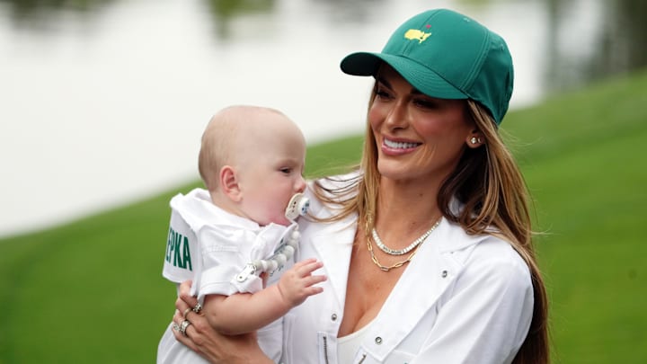 Brooks Koepka's wife Jena Sims carries their son Crew down the No. 6 fairway during the Par 3 Contest at Augusta National.