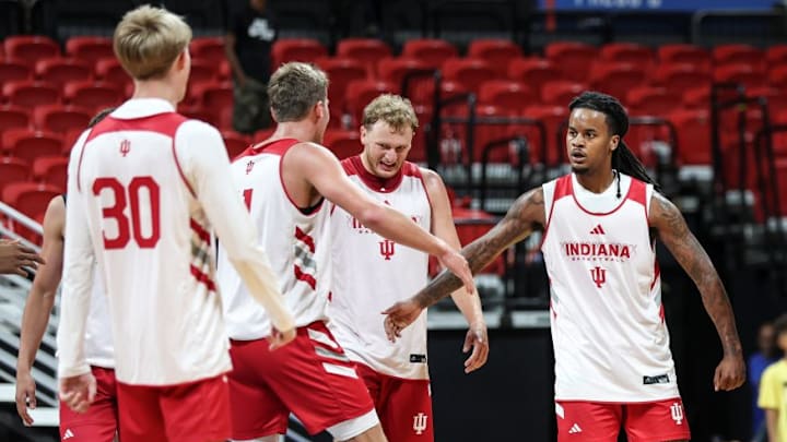 Indiana basketball guard Lamar Wilkerson high-fives teammate Trent Sisley, standing between Tucker DeVries and Ian Stephens.