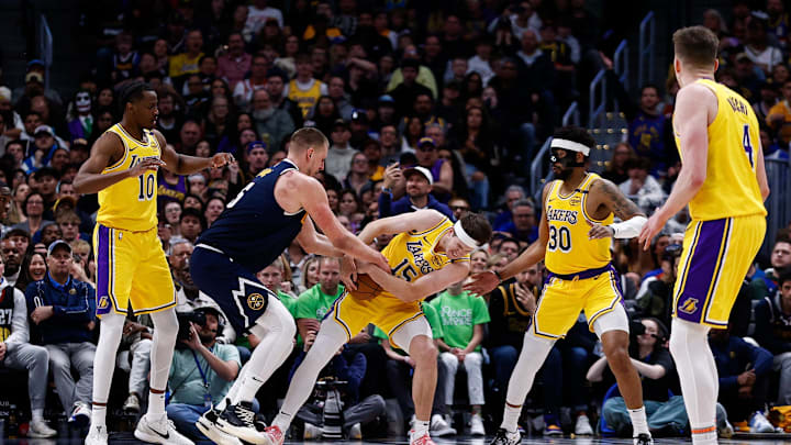 Mar 14, 2025; Denver, Colorado, USA; Los Angeles Lakers guard Austin Reaves (15) steals the ball away from Denver Nuggets center Nikola Jokic (15) as center Christian Koloko (10) and guard Jordan Goodwin (30) defend in the fourth quarter at Ball Arena. Mandatory Credit: Isaiah J. Downing-Imagn Images