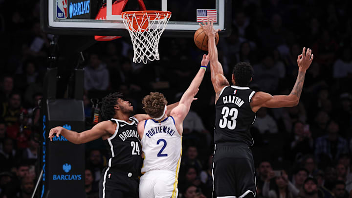 Feb 5, 2024; Brooklyn, New York, USA; Brooklyn Nets center Nic Claxton (33) blocks a shot by Golden State Warriors guard Brandin Podziemski (2) as guard Cam Thomas (24) defends during the first quarter against the Brooklyn Nets at Barclays Center. Mandatory Credit: Vincent Carchietta-Imagn Images