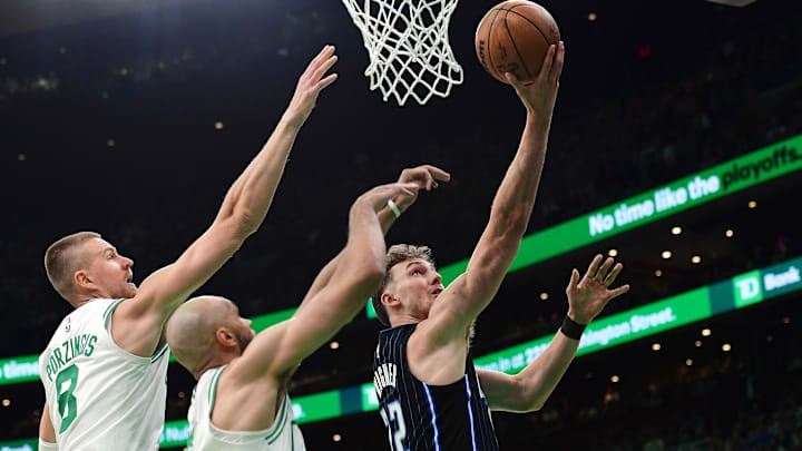 Orlando Magic forward Franz Wagner (22) drives to the basket past Boston Celtics center Kristaps Porzingis (8) and Boston Celtics guard Derrick White (9) during the first half at TD Garden. Orlando Magic forward Franz Wagner (22) drives to the basket past Boston Celtics center Kristaps Porzingis (8) and Boston Celtics guard Derrick White (9) during the first half at TD Garden.