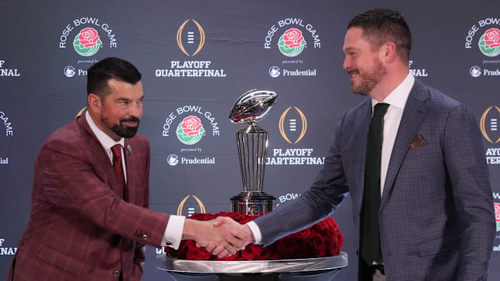 Dec 31, 2024; Los Angeles, California, USA; Ohio State Buckeyes head coach Ryan Day (left) and Oregon Ducks head coach Dan Lanning shake hands with the Leishman Trophy as a backdrop during the Rose Bowl head coaches press conference at Sheraton Grand LA. Mandatory Credit: Kirby Lee-Imagn Images