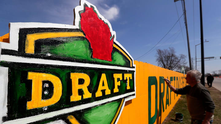Christopher Handler paints a new 2025 NFL Draft-themed fence along Lombardi Avenue on April 12, 2025, in Green Bay, Wis.