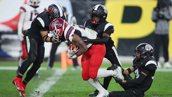 Aliquippa's QaLil Goode (14), Gavin Wilcox (13), and Arison Walker (15) attempt to hold back McKeesport's Kemon Spell (20) from scoring a touchdown during the second half of the WPIAL 4A Championship game Friday evening at Acrisure Stadium in Pittsburgh, PA.