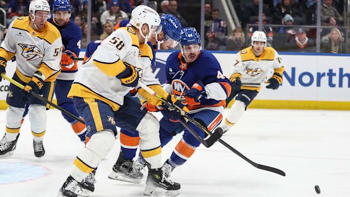 Jan 31, 2026; Elmont, New York, USA;  Nashville Predators left wing Michael Bunting (58) battles for control of the puck with New York Islanders defenseman Scott Mayfield (24) and center Jean-Gabriel Pageau (44) in the third period at UBS Arena. Mandatory Credit: Wendell Cruz-Imagn Images
