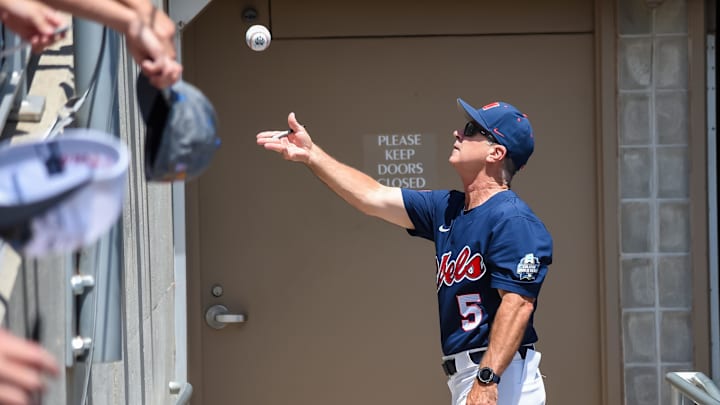 Jun 26, 2022; Omaha, NE, USA; Ole Miss Rebels head coach Mike Bianco tosses a ball to a fan before the game against the Oklahoma Sooners at Charles Schwab Field. Mandatory Credit: Steven Branscombe-Imagn Images