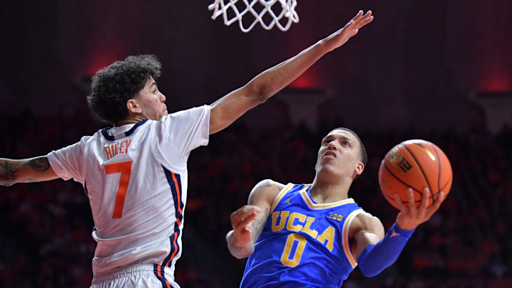 Feb 11, 2025; Champaign, Illinois, USA;  UCLA Bruins guard Kobe Johnson (0) drives to the basket as Illinois Fighting Illini forward Will Riley (7) defends during the second half at State Farm Center. Mandatory Credit: Ron Johnson-Imagn Images