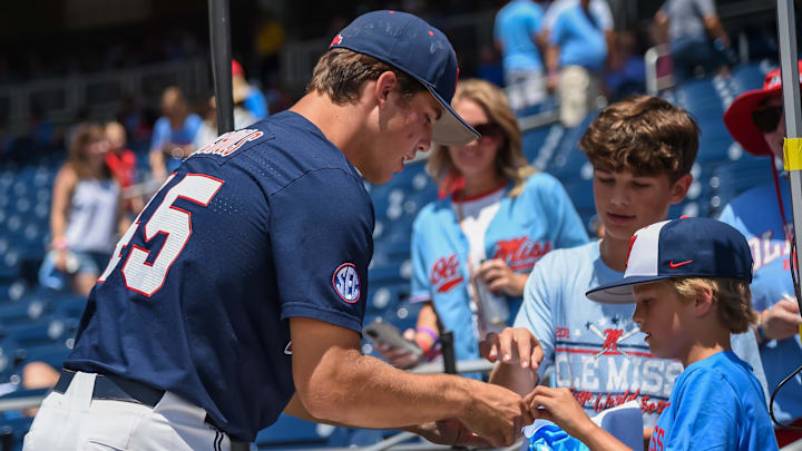 Jun 26, 2022; Omaha, NE, USA; Ole Miss Rebels pitcher Mason Nichols (45) signs a baseball for a fan before the game against the Oklahoma Sooners at Charles Schwab Field. Mandatory Credit: Steven Branscombe-Imagn Images Jun 26, 2022; Omaha, NE, USA; Ole Miss Rebels pitcher Mason Nichols (45) signs a baseball for a fan before the game against the Oklahoma Sooners at Charles Schwab Field. Mandatory Credit: Steven Branscombe-Imagn Images