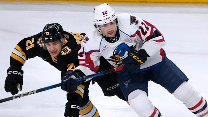 PBruin Matthew Poitras reaches in for the puck on Thunderbird Dylan Peterson in the first period.