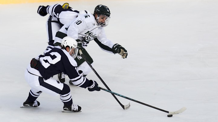 Jan 31, 2026; State College, PA, USA; Michigan State Spartans forward Tommi Mannisto (10) and Penn State Nittany Lions forward Ben Schoen (12) battle for the puck during the third period at Beaver Stadium. Mandatory Credit: Matthew O'Haren-Imagn Images