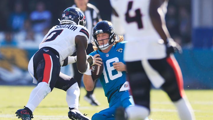 Jacksonville Jaguars quarterback Trevor Lawrence (16) slides for a down as Houston Texans linebacker Azeez Al-Shaair (0) makes a late hit during the second quarter of an NFL football matchup Sunday, Dec. 1, 2024 at EverBank Stadium in Jacksonville, Fla.
