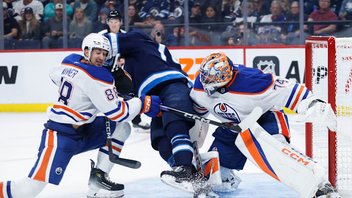 Winnipeg Jets goalie Arvid Holm (75) jostles for position with Edmonton Oilers defenseman Max Wanner (88)