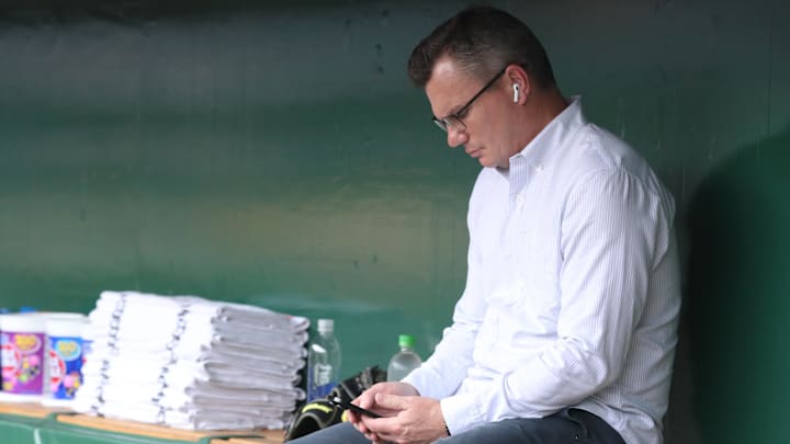 Apr 29, 2025; Pittsburgh, Pennsylvania, USA; Pittsburgh Pirates general manager Ben Cherington checks his phone in he dugout before the game against the Chicago Cubs at PNC Park. Mandatory Credit: Charles LeClaire-Imagn Images