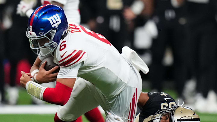 Oct 5, 2025; New Orleans, Louisiana, USA; New Orleans Saints safety Jonas Sanker (33) brings down New York Giants quarterback Jaxson Dart (6) during the fourth quarter at Caesars Superdome.  
