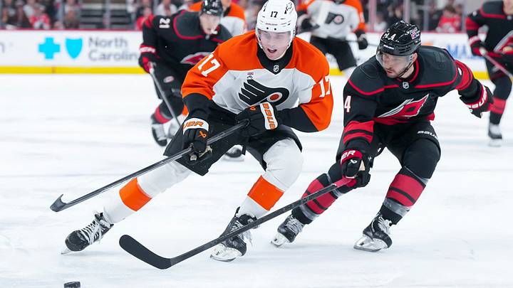 Oct 11, 2025; Raleigh, North Carolina, USA;  Philadelphia Flyers center Jett Luchanko (17) has the puck poked away by Carolina Hurricanes defenseman Shayne Gostisbehere (4) during the second period at Lenovo Center.