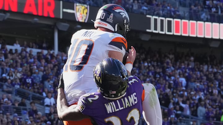 Nov 3, 2024; Baltimore, Maryland, USA; Denver Broncos quarterback Bo Nix (10) leaps to catch a second quarter touchdown defended by Baltimore Ravens safety Marcus Williams (32) at M&T Bank Stadium. 