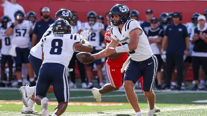 Utah State Aggies quarterback Grady Brosterhous (9) hands the ball off to running back Javen Jacobs (8) during the second half at Rice-Eccles Stadium. Utah State Aggies quarterback Grady Brosterhous (9) hands the ball off to running back Javen Jacobs (8) during the second half at Rice-Eccles Stadium.