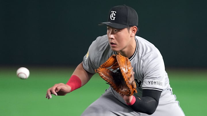 Mar 15, 2025; Bunkyo, Tokyo, Japan; Yomiuri Giants first baseman Kazuma Okamoto (25) fields a ground ball against the Los Angeles Dodgers during the fifth inning at Tokyo Dome. Mandatory Credit: Darren Yamashita-Imagn Images