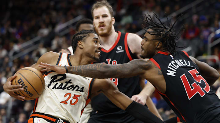 Nov 25, 2024; Detroit, Michigan, USA;  Detroit Pistons guard Jaden Ivey (23) is defended by Toronto Raptors center Jakob Poeltl (19) and guard Davion Mitchell (45) in the first half at Little Caesars Arena. Mandatory Credit: Rick Osentoski-Imagn Images