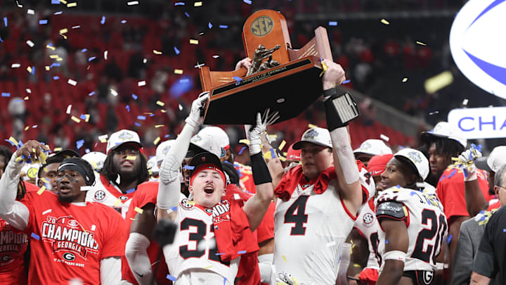 Dec 6, 2025; Atlanta, GA, USA; Georgia Bulldogs running back Cash Jones (32) and Georgia Bulldogs tight end Oscar Delp (4) lift the SEC Championship trophy after the game against the Alabama Crimson Tide during the 2025 SEC Championship game at Mercedes-Benz Stadium. Mandatory Credit: Brett Davis-Imagn Images