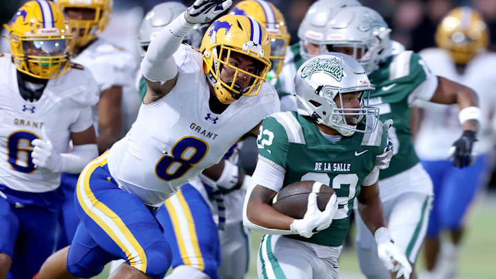 Running back Derrick Blanche (right) of De La Salle attempts to elude Grant linebacker Jeremiah Tuiileila.