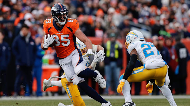 Dec 31, 2023; Denver, Colorado, USA; Denver Broncos tight end Lucas Krull (85) runs through the tackle of Los Angeles Chargers linebacker Nick Niemann (31) as cornerback Essang Bassey (27) defends in the second quarter at Empower Field at Mile High. Mandatory Credit: Isaiah J. Downing-USA TODAY Sports