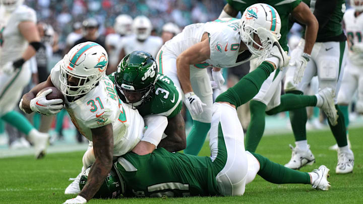 Miami Dolphins running back Raheem Mostert (31) gains a few tough yards as New York Jets safety Jordan Whitehead (3) and safety Ashtyn Davis (21) converge on the play during the first half of an NFL game at Hard Rock Stadium in Miami Gardens, Dec. 17, 2023.
