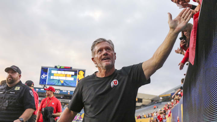 Utah Utes head coach Kyle Whittingham celebrates with fans after defeating the West Virginia Mountaineers at Milan Puskar Stadium.
