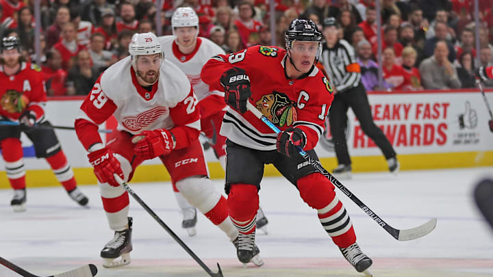 Jan 5, 2020; Chicago, Illinois, USA; Chicago Blackhawks center Jonathan Toews (19) makes a pass with Detroit Red Wings left wing Brendan Perlini (29) in pursuit during the first period at the United Center. Mandatory Credit: Dennis Wierzbicki-Imagn Images