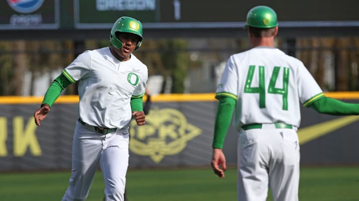 Oregon's Jacob Walsh, left, is congratulated by head baseball coach Mark Wasikowski as he heads home.