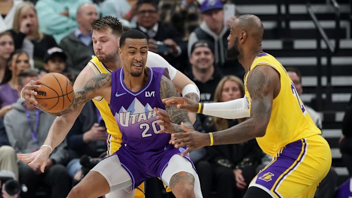 Feb 12, 2025; Salt Lake City, Utah, USA;  Utah Jazz forward John Collins (20) tries to keep the ball away from Los Angeles Lakers guard Luka Doncic (77) and forward LeBron James (23) during the first quarter at Delta Center. Mandatory Credit: Chris Nicoll-Imagn Images