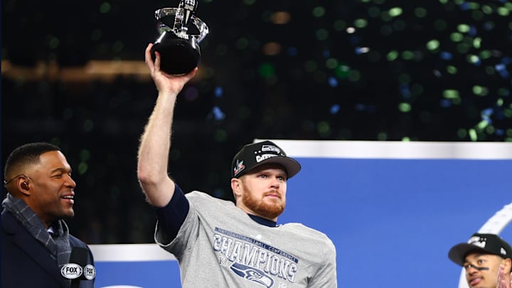 Jan 25, 2026; Seattle, WA, USA; Seattle Seahawks quarterback Sam Darnold (14) celebrates with the trophy on the podium after defeating the Los Angeles Rams in the 2026 NFC Championship Game at Lumen Field.