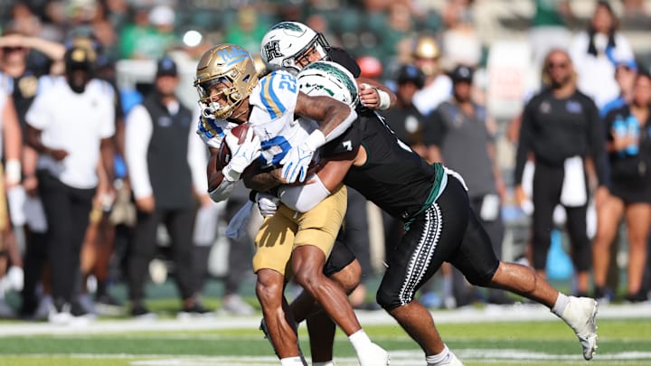 Aug 31, 2024; Honolulu, Hawaii, USA; UCLA Bruins running back Keegan Jones (22) gets pulled down by the Hawaii Rainbow Warriors linebacker Jalen Smith (3) and defensive back Peter Manuma (1) during the fourth quarter of an NCAA college football game at the Clarence T.C. Ching Athletics Complex. Mandatory Credit: Marco Garcia-Imagn Images