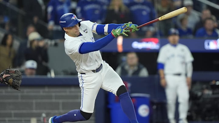 George Springer hits a single in a white Blue Jays uniform