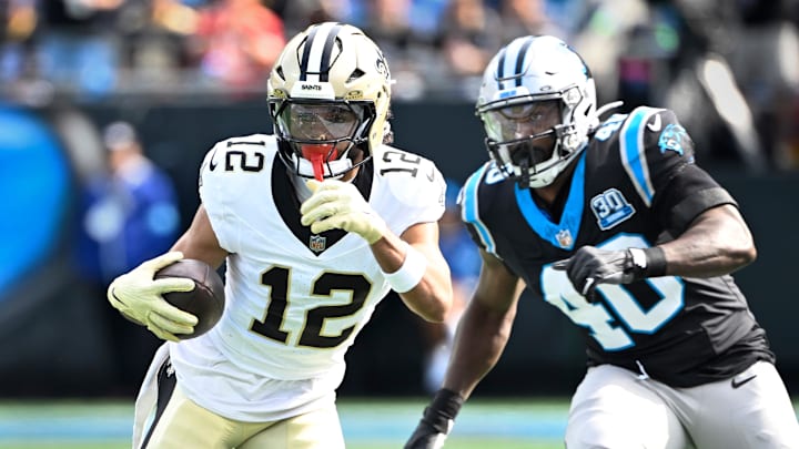 Nov 3, 2024; Charlotte, North Carolina, USA; New Orleans Saints wide receiver Chris Olave (12) with the ball as Carolina Panthers linebacker Charles Harris (40) defends in the first quarter at Bank of America Stadium. Mandatory Credit: Bob Donnan-Imagn Images

