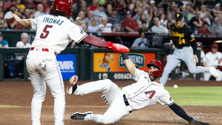 May 27, 2025; Phoenix, Arizona, USA; Arizona Diamondbacks base runner Jordan Lawlar (right) celebrates with Alek Thomas as he slides into home to score against the Pittsburgh Pirates in the fourth inning at Chase Field. Mandatory Credit: Mark J. Rebilas-Imagn Images