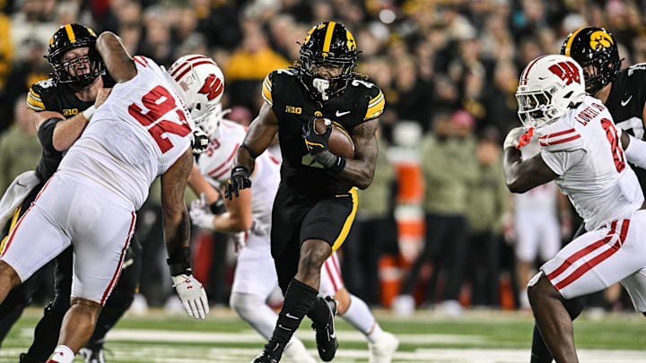 Nov 2, 2024; Iowa City, Iowa, USA;  Iowa Hawkeyes running back Kaleb Johnson (2) runs for a 16 yard touchdown as Wisconsin Badgers defensive lineman Curt Neal (92) and linebacker Leon Lowery Jr. (8) attempt to make the tackle during the second quarter at Kinnick Stadium. Mandatory Credit: Jeffrey Becker-Imagn Images