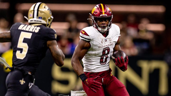 Dec 15, 2024; New Orleans, Louisiana, USA;  Washington Commanders running back Brian Robinson Jr. (8) rushes against New Orleans Saints cornerback Will Harris (5) during the first half at Caesars Superdome. Mandatory Credit: Stephen Lew-Imagn Images