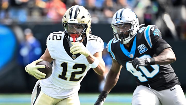 Nov 3, 2024; Charlotte, North Carolina, USA; New Orleans Saints wide receiver Chris Olave (12) with the ball as Carolina Panthers linebacker Charles Harris (40) defends in the first quarter at Bank of America Stadium. Mandatory Credit: Bob Donnan-Imagn Images
