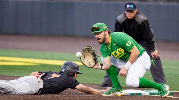 Oregon State infielder AJ Singer, left, dives safely back to first base under cover from Oregon infielder Gabe Miranda as the Oregon Ducks host the Oregon State Beavers on March 3, 2026, at PK Park in Eugene, Oregon. Oregon State infielder AJ Singer, left, dives safely back to first base under cover from Oregon infielder Gabe Miranda as the Oregon Ducks host the Oregon State Beavers on March 3, 2026, at PK Park in Eugene, Oregon.