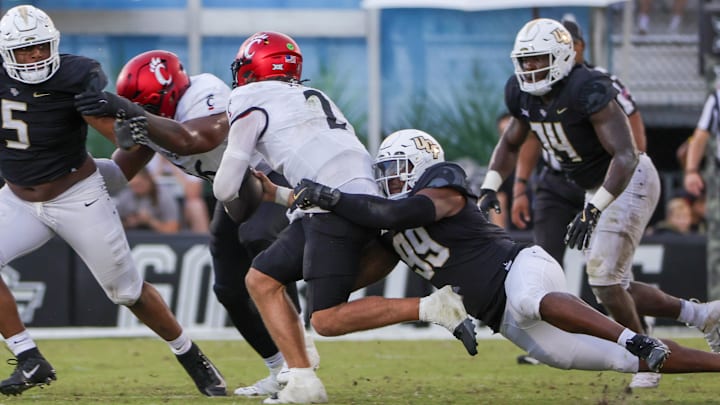 Oct 12, 2024; Orlando, Florida, USA; Cincinnati Bearcats quarterback Brendan Sorsby (2) is sacked by UCF Knights defensive end Jamaal Johnson (99) during the second half at FBC Mortgage Stadium. Mandatory Credit: Mike Watters-Imagn Images