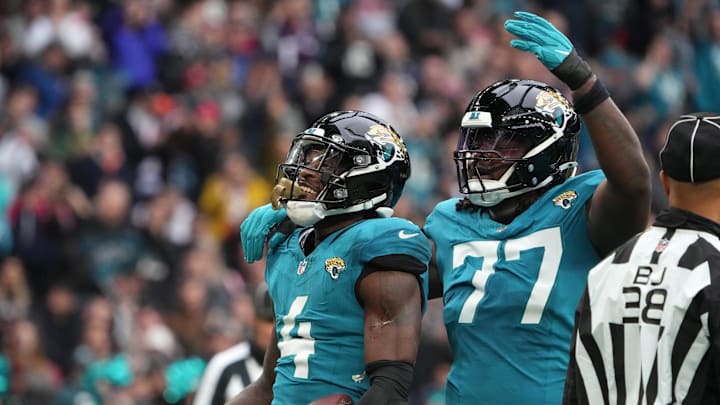 Oct 20, 2024; London, United Kingdom; Jacksonville Jaguars running back Tank Bigsby (4) celebrates with offensive tackle Anton Harrison (77) after scoring on a 1-yard touchdown run against the New England Patriots in the first half of an NFL International Series game at Wembley Stadium. Mandatory Credit: Kirby Lee-Imagn Images