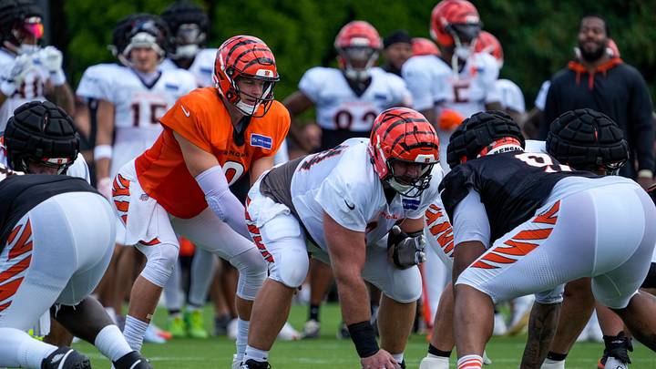 Cincinnati Bengals quarterback Joe Burrow (9) takes a snap from center Ted Karras (64) during practice at the Paycor Stadium practice facility in downtown Cincinnati on Monday, Aug. 3, 2026.