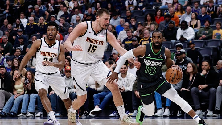 Minnesota Timberwolves guard Mike Conley controls the ball under pressure from Denver Nuggets center Nikola Jokic in the first quarter at Ball Arena in Denver on April 1, 2025.
